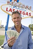 Mid-adult man holding notes in front of Welcome to Las Vegas sign ... Mid-adult man holding notes in front of Welcome to Las Vegas sign ...